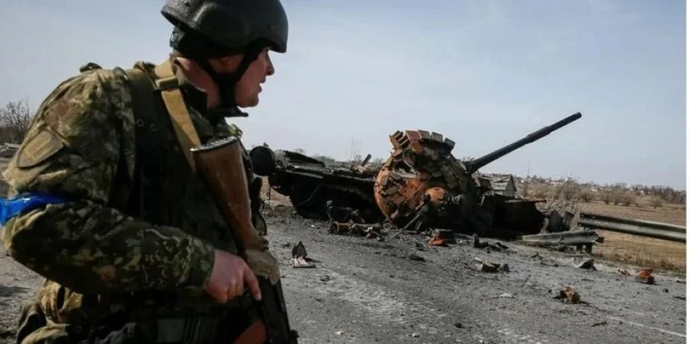 Український військовий біля уламків російського танка у Київській області, REUTERS/Gleb Garanich